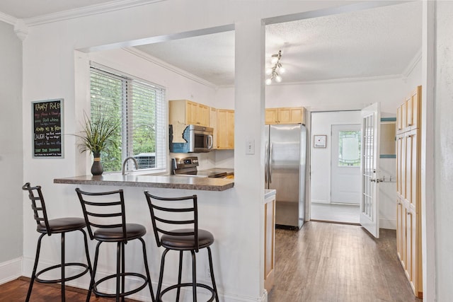 332 2nd St, New Richmond, WI 54017 - kitchen with appliances with stainless steel finishes, light brown cabinets, dark wood-style floors, plenty of natural light, and ornamental molding