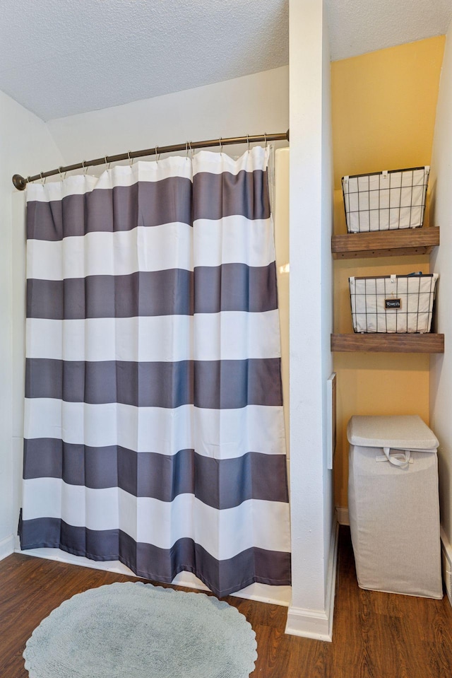 332 2nd St, New Richmond, WI 54017 - bathroom featuring wood finished floors, baseboards, a shower with shower curtain, and a textured ceiling