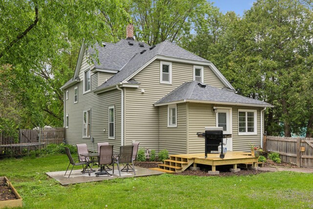 332 2nd St, New Richmond, WI 54017 - back of house with a shingled roof, a deck, a chimney, and a patio area