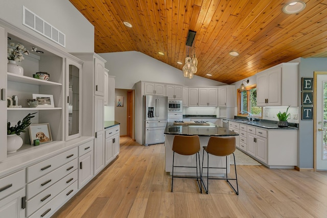 8081 45th Ave SW, Raymond, MN 56282 - kitchen with appliances with stainless steel finishes, white cabinetry, a sink, vaulted ceiling, and a breakfast bar