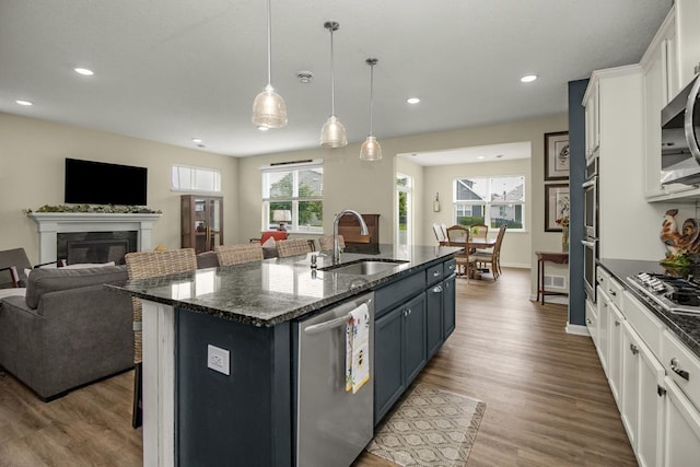 4745 Copper Cir, Woodbury, MN 55129 - kitchen featuring appliances with stainless steel finishes, open floor plan, dark wood-type flooring, a kitchen breakfast bar, and a kitchen island with sink