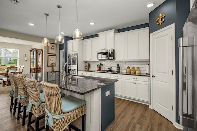 4745 Copper Cir, Woodbury, MN 55129 - kitchen featuring stainless steel appliances, backsplash, a kitchen breakfast bar, dark wood-type flooring, and recessed lighting