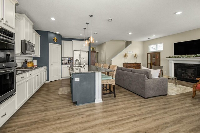 4745 Copper Cir, Woodbury, MN 55129 - kitchen with appliances with stainless steel finishes, a kitchen breakfast bar, open floor plan, tasteful backsplash, and white cabinets