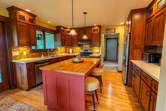 N12011 County Road Ss, Otter Creek Twp, WI 54772 - kitchen with stainless steel appliances, under cabinet range hood, wood counters, light wood finished floors, and a breakfast bar