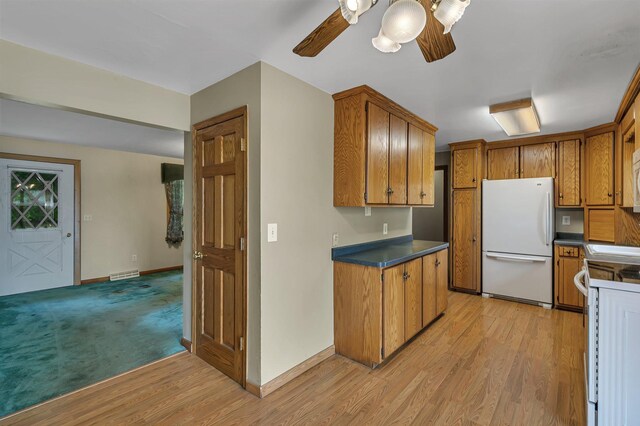 16736 County Road 49, Cold Spring, MN 56320 - kitchen featuring freestanding refrigerator, brown cabinetry, dark countertops, a ceiling fan, and light wood-style floors