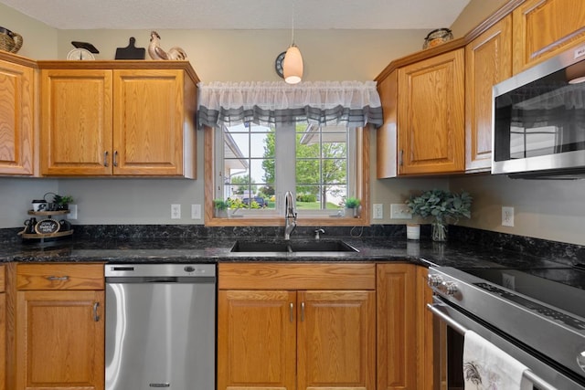2475 Mossy Creek Dr NE, Owatonna, MN 55060 - kitchen with appliances with stainless steel finishes, dark stone counters, brown cabinets, and hanging light fixtures