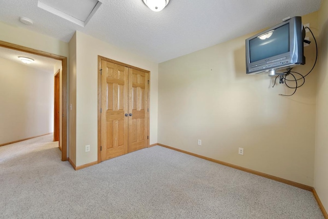 2475 Mossy Creek Dr NE, Owatonna, MN 55060 - unfurnished bedroom featuring attic access, carpet flooring, a closet, and a textured ceiling