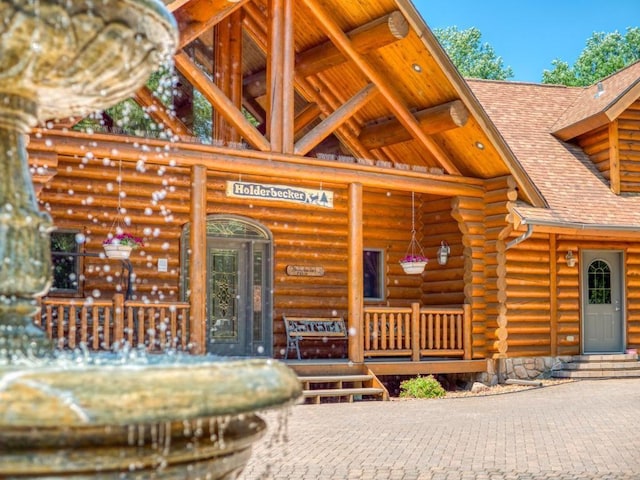 10719 Lumberjack Rd NW, Alaska Twp, MN 56667 - view of exterior entry featuring covered porch, log siding, and a shingled roof