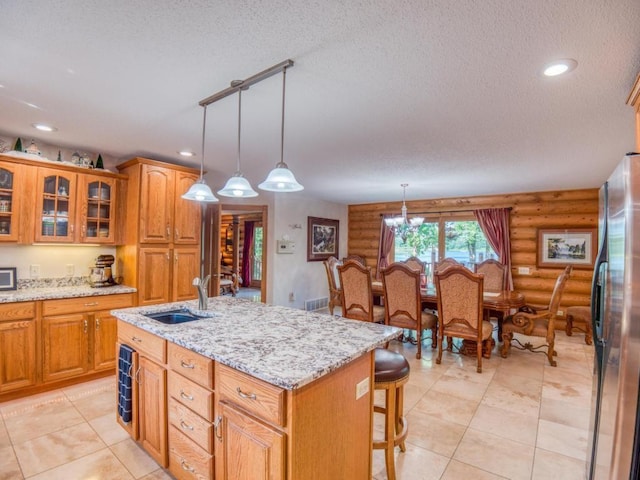 10719 Lumberjack Rd NW, Alaska Twp, MN 56667 - kitchen featuring a sink, freestanding refrigerator, a textured ceiling, rustic walls, and an island with sink