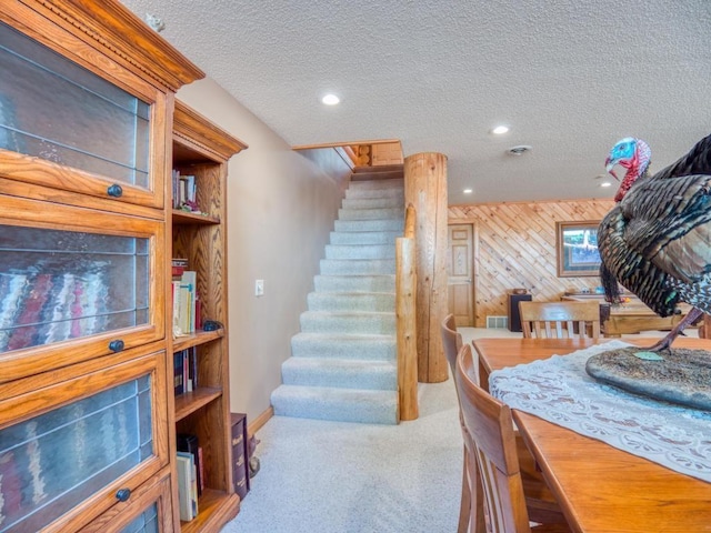 10719 Lumberjack Rd NW, Alaska Twp, MN 56667 - carpeted dining space with stairway, a textured ceiling, recessed lighting, wood walls, and baseboards