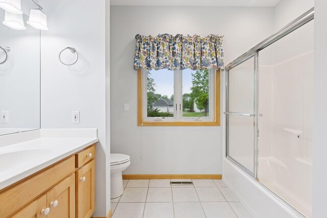9536 Windflower Pl, Champlin, MN 55316 - bathroom with tile patterned floors, toilet, baseboards, vanity, and bath / shower combo with glass door