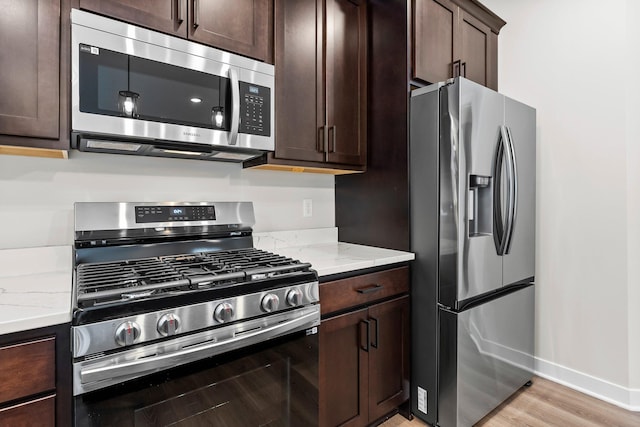 1700 Misty Cir, Buffalo, MN 55313 - kitchen with stainless steel appliances, dark brown cabinets, light wood-type flooring, baseboards, and light stone countertops