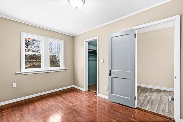 319 60th Ave W, Duluth, MN 55807 - unfurnished bedroom featuring wood finished floors, crown molding, a spacious closet, a closet, and baseboards