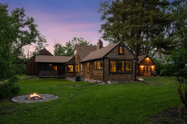 605 Stubbs Bay Rd, Orono, MN 55356 - back of house at dusk with an outdoor fire pit, a chimney, a yard, and roof with shingles