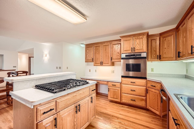 3544 166th Ln NW, Andover, MN 55304 - kitchen featuring appliances with stainless steel finishes, light wood-style floors, a kitchen island, light countertops, and a textured ceiling