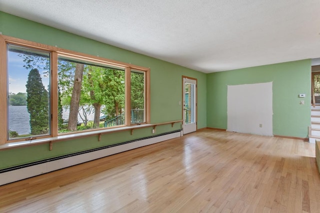364 Owasso Blvd N, Shoreview, MN 55126 - empty room featuring baseboard heating, healthy amount of natural light, wood finished floors, and a textured ceiling
