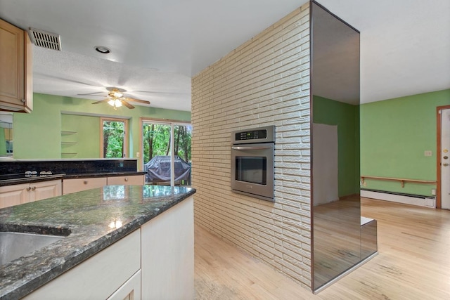 364 Owasso Blvd N, Shoreview, MN 55126 - kitchen featuring stainless steel oven, a baseboard heating unit, light wood finished floors, ceiling fan, and dark stone counters