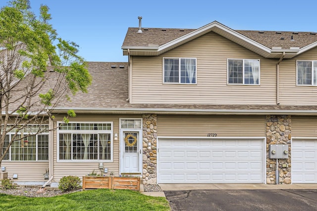 12729 Eagle St NW, Coon Rapids, MN 55448 - view of property featuring roof with shingles, a garage, stone siding, and asphalt driveway