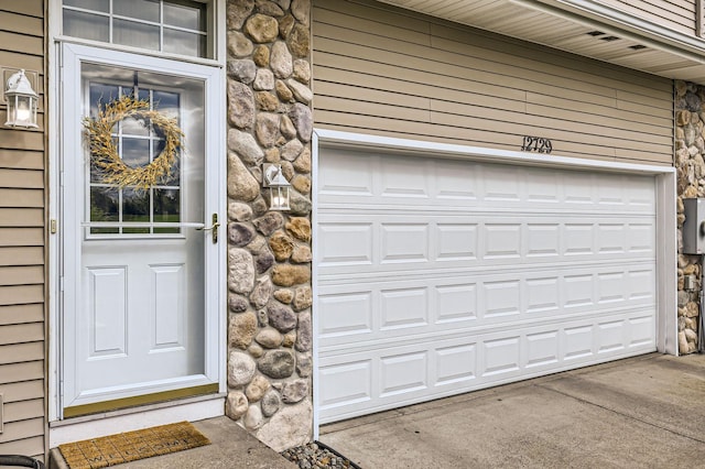 12729 Eagle St NW, Coon Rapids, MN 55448 - property entrance with stone siding, a garage, and driveway