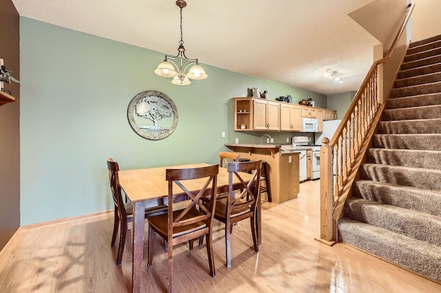 12729 Eagle St NW, Coon Rapids, MN 55448 - dining space with stairs, light wood-style floors, a chandelier, baseboards, and a textured ceiling