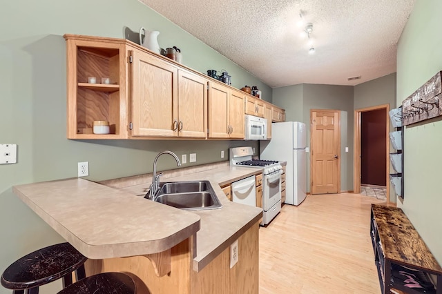 12729 Eagle St NW, Coon Rapids, MN 55448 - kitchen with a sink, white appliances, a peninsula, a textured ceiling, and a breakfast bar