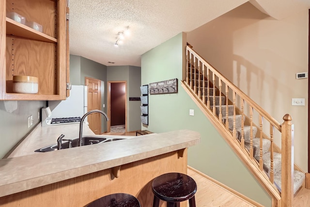 12729 Eagle St NW, Coon Rapids, MN 55448 - kitchen with freestanding refrigerator, a peninsula, a textured ceiling, a breakfast bar area, and light countertops