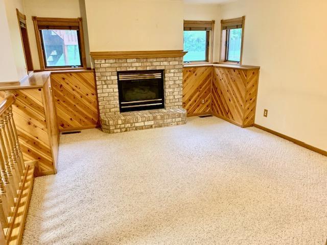 701 Parkview Ln N, Champlin, MN 55316 - unfurnished living room featuring wooden walls, carpet, a wainscoted wall, and a fireplace