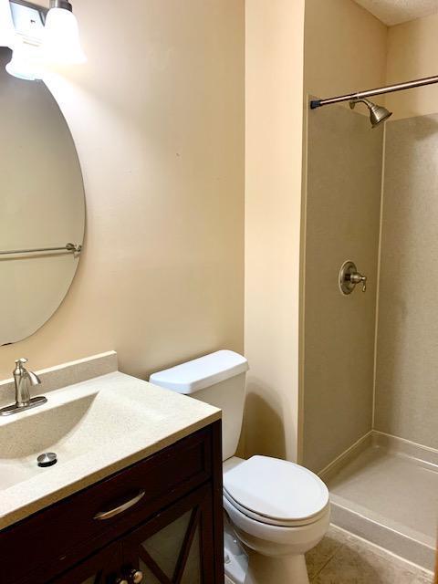 701 Parkview Ln N, Champlin, MN 55316 - bathroom featuring toilet, vanity, a shower, and tile patterned floors