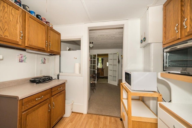 9298 Park Ave, Solon Springs, WI 54873 - kitchen featuring white microwave, brown cabinetry, light countertops, light wood-type flooring, and stainless steel microwave