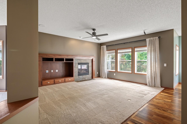4231 Maple Hurst Dr N, Rockford, MN 55373 - unfurnished living room featuring a ceiling fan, a textured ceiling, wood finished floors, and a tile fireplace