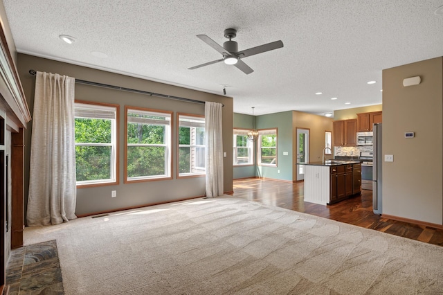 4231 Maple Hurst Dr N, Rockford, MN 55373 - unfurnished living room with a textured ceiling, a ceiling fan, a chandelier, dark wood-type flooring, and recessed lighting