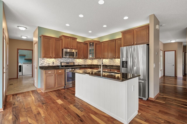 4231 Maple Hurst Dr N, Rockford, MN 55373 - kitchen with stainless steel appliances, washing machine and clothes dryer, backsplash, dark wood-type flooring, and brown cabinetry