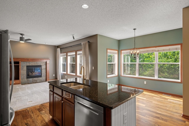 4231 Maple Hurst Dr N, Rockford, MN 55373 - kitchen with stainless steel appliances, wood finished floors, open floor plan, a textured ceiling, and a tiled fireplace