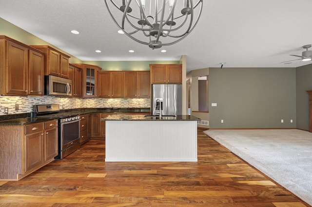 4231 Maple Hurst Dr N, Rockford, MN 55373 - kitchen with stainless steel appliances, open floor plan, brown cabinets, dark wood finished floors, and a kitchen island with sink