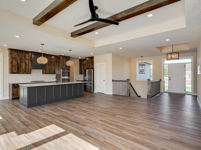 20666 Tamarack St NW, Oak Grove, MN 55011 - kitchen featuring appliances with stainless steel finishes, light countertops, light wood-type flooring, open floor plan, and beamed ceiling