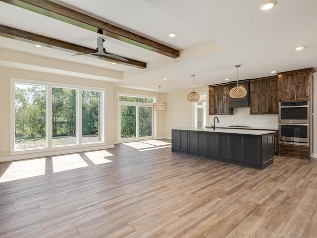 20666 Tamarack St NW, Oak Grove, MN 55011 - kitchen with stainless steel double oven, light countertops, decorative backsplash, light wood-style flooring, and beamed ceiling