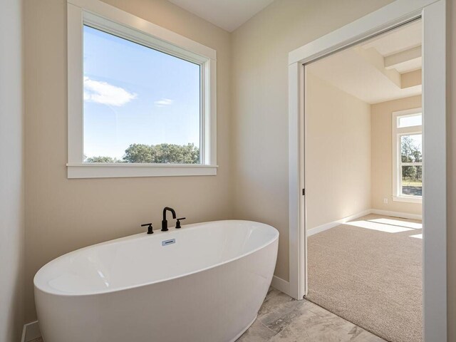 20666 Tamarack St NW, Oak Grove, MN 55011 - bathroom featuring a soaking tub, baseboards, and marble finish flooring