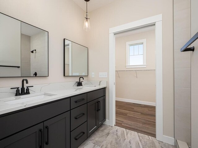 20666 Tamarack St NW, Oak Grove, MN 55011 - bathroom with baseboards, double vanity, marble finish flooring, tiled shower, and a walk in closet
