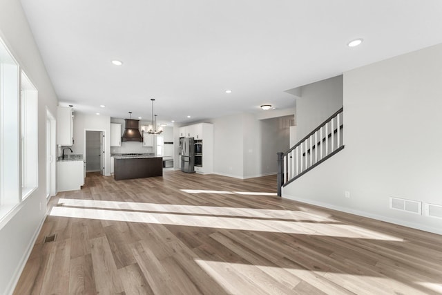 1708 Misty Cir, Buffalo, MN 55313 - unfurnished living room with light wood finished floors, a chandelier, baseboards, recessed lighting, and stairs