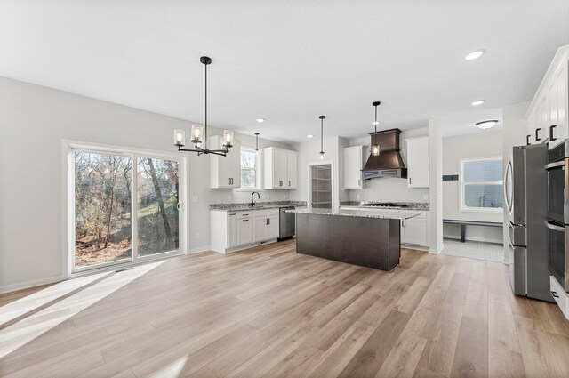 1708 Misty Cir, Buffalo, MN 55313 - kitchen featuring custom range hood, appliances with stainless steel finishes, a chandelier, a kitchen island, and light wood-style flooring