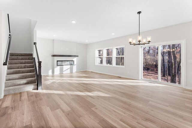 1708 Misty Cir, Buffalo, MN 55313 - unfurnished living room featuring a glass covered fireplace, a chandelier, light wood-style flooring, stairway, and recessed lighting