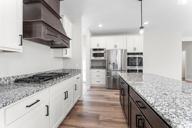 1708 Misty Cir, Buffalo, MN 55313 - kitchen with appliances with stainless steel finishes, custom range hood, white cabinetry, light stone countertops, and decorative light fixtures