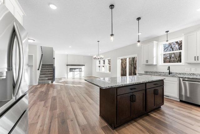 1708 Misty Cir, Buffalo, MN 55313 - kitchen with stainless steel appliances, light wood-style flooring, dark brown cabinetry, white cabinetry, and light stone countertops