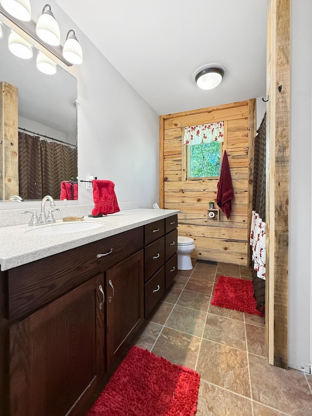 7215 Little Dip Ln NE, Bemidji, MN 56601 - full bathroom with vanity, toilet, stone finish floors, and wood walls
