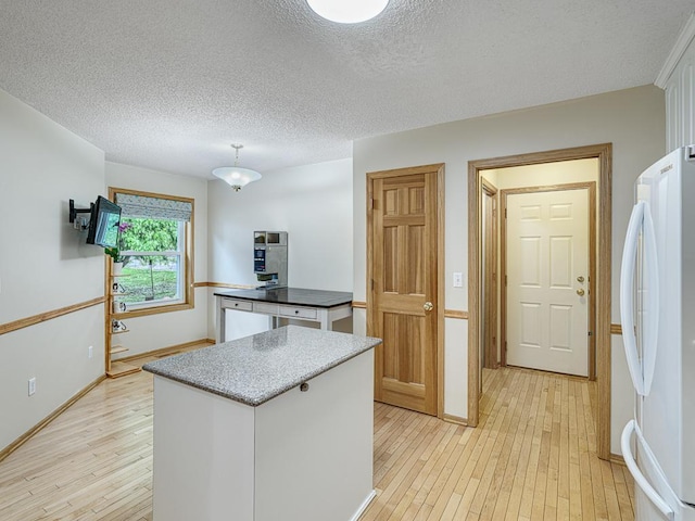 5420 Saxony Ct, White Bear Twp, MN 55110 - kitchen with freestanding refrigerator, a center island, light wood-type flooring, a textured ceiling, and baseboards