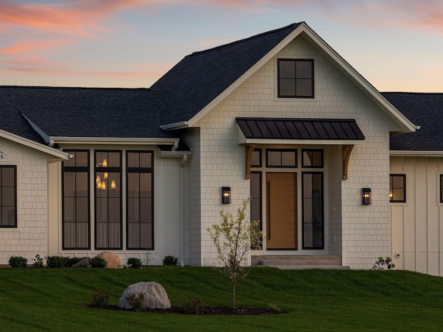 7937 Eldorado Rd, Credit River Twp, MN 55372 - exterior entry at dusk featuring a shingled roof, a yard, a standing seam roof, and metal roof