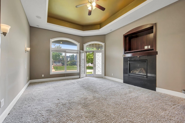 18141 87th Ave N, Maple Grove, MN 55311 - unfurnished living room featuring a glass covered fireplace, carpet floors, a raised ceiling, baseboards, and a ceiling fan