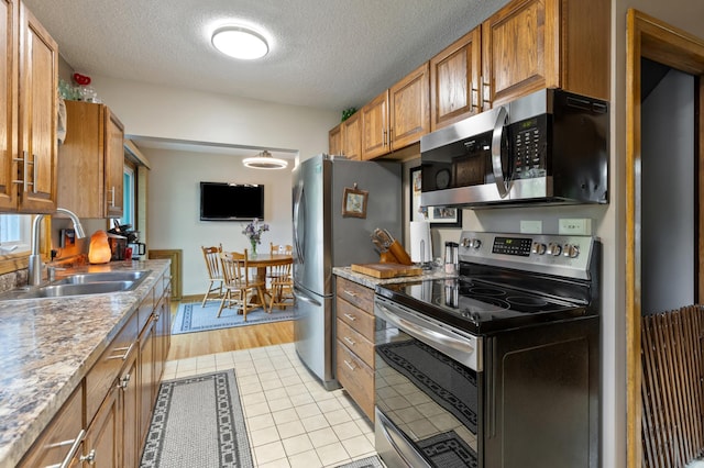 2196 Waukon Ave, Saint Paul, MN 55119 - kitchen with appliances with stainless steel finishes, a sink, brown cabinetry, a textured ceiling, and light tile patterned floors