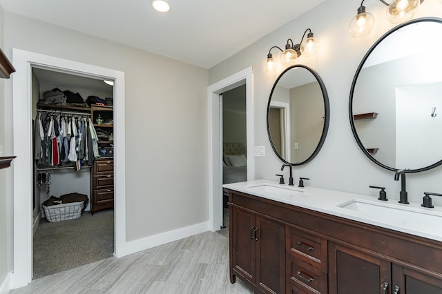 9420 Fabian St NE, Kalmar Twp, MN 55920 - bathroom featuring double vanity, a spacious closet, baseboards, and wood finished floors