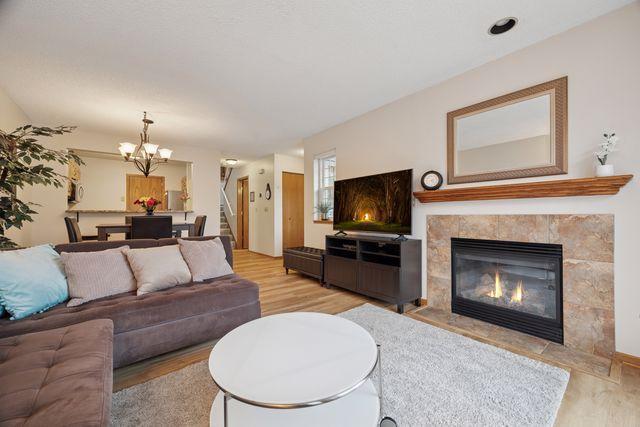 1925 Shenandoah Ct Unit G, Plymouth, MN 55447 - living room with light wood-type flooring, a chandelier, a tile fireplace, and stairs